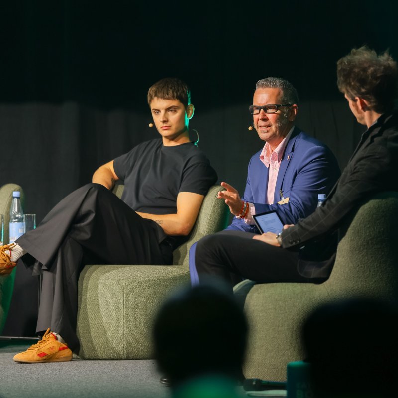Panel-Gespräch auf der Bühne sitzen vier Männer in Sesseln